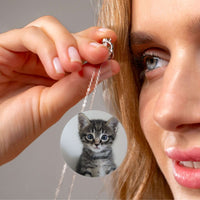 Thumbnail for A woman holding the Infinite Photo Necklace featuring a custom photo of a playful kitten by Brother & Sisters.