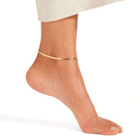 Thumbnail for Layla gold herringbone snake chain anklet worn on tanned ankle with cream knit skirt — 18K gold-plated flat snake chain for everyday wear