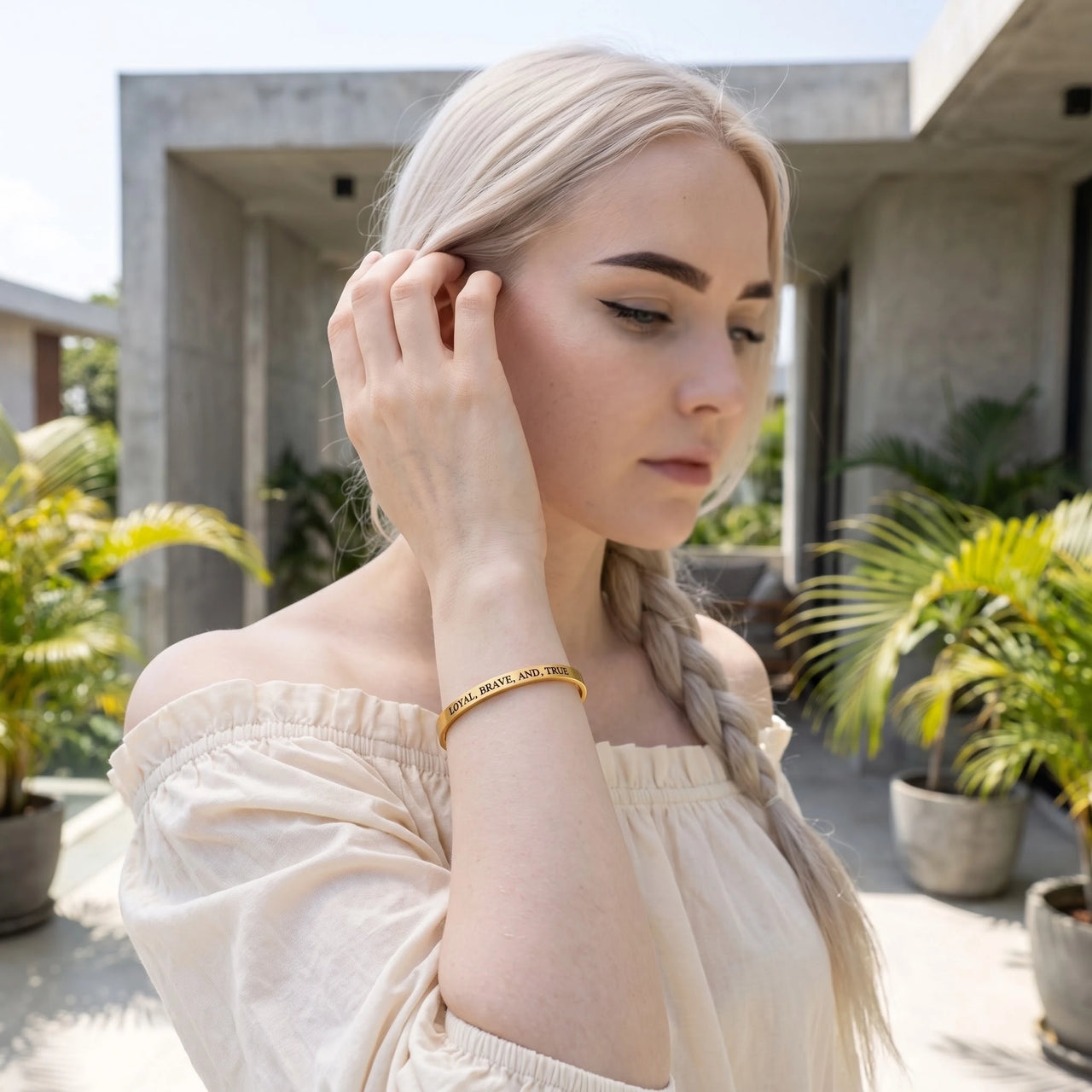 Woman gently touching her Loyal, Brave, And, True bracelet in gold | SKU: lbat-g