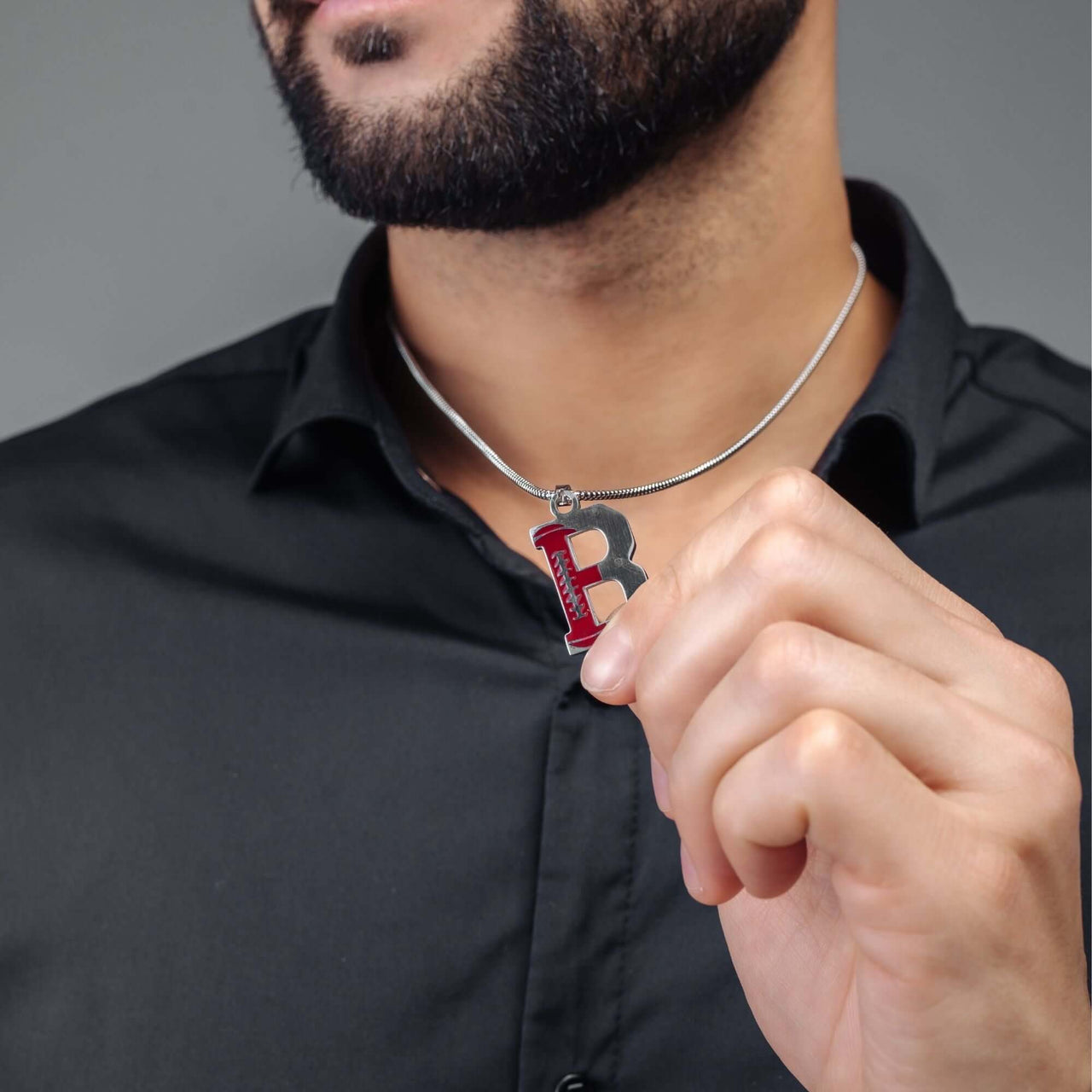 Man holding Silver Rugby Initial Necklace with letter 'B', a bold personalized men's necklace by Brother & Sisters.