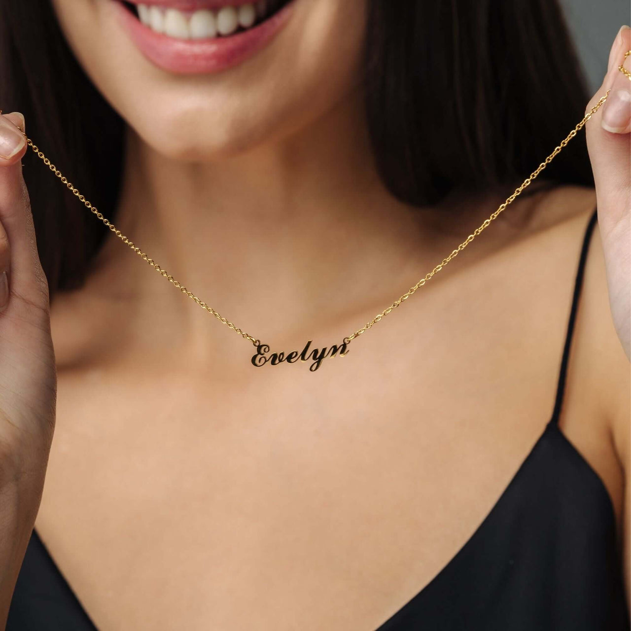 Minimalist Name Necklace held by a woman, showcasing gold personalized design from Brother & Sisters.