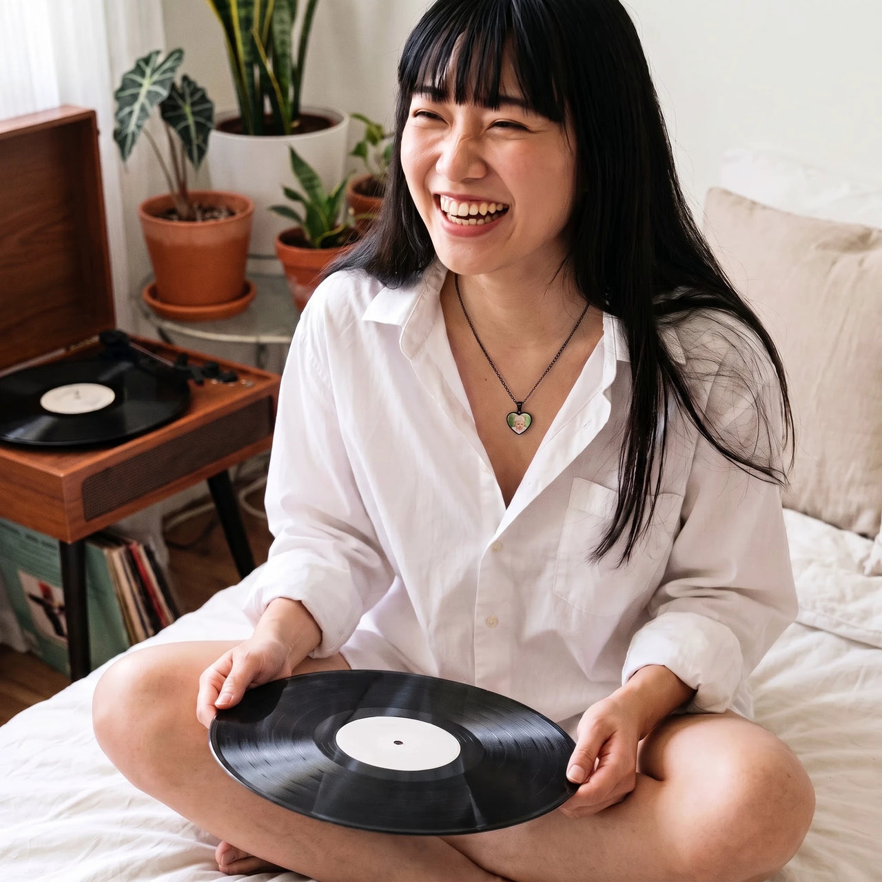 Woman with a vinyl record, wearing the black secret heart photo necklace | SKU: TPH-CHTN-BLACK-SMALL