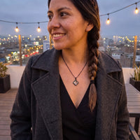 Thumbnail for Smiling woman with a braid in a grey coat on a rooftop at dusk, wearing the black secret clover photo necklace | SKU: TPH-CLVN-BLACK