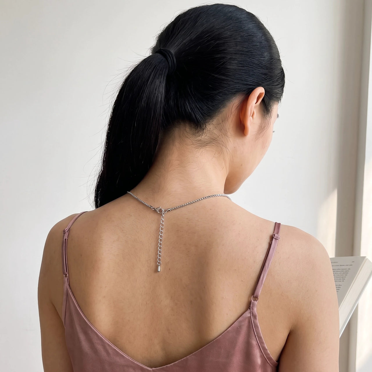 Back of the neck of a woman with a dark ponytail showing the clasp and extension chain of the silver clover photo necklace | SKU: TPH-CLVN-SILVER