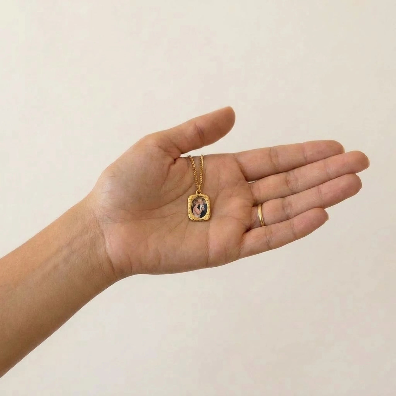Gold oval pendant resting in her palm, real small size, her parents' photo inside | SKU: TPH-OVLN-GOLD