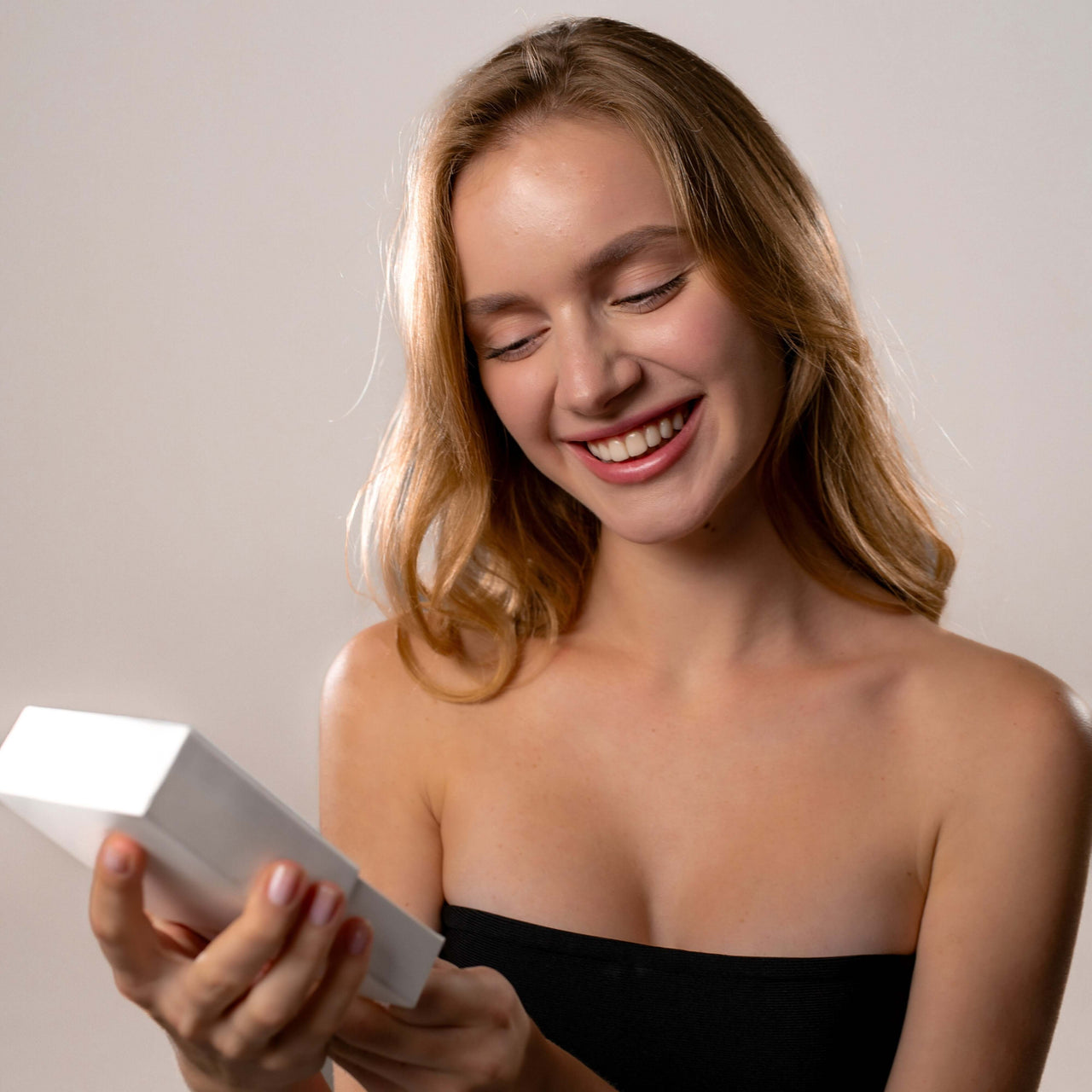 Smiling woman holding a gift box, showcasing joy and excitement with the Cat Photo Necklace from Brother & Sisters.