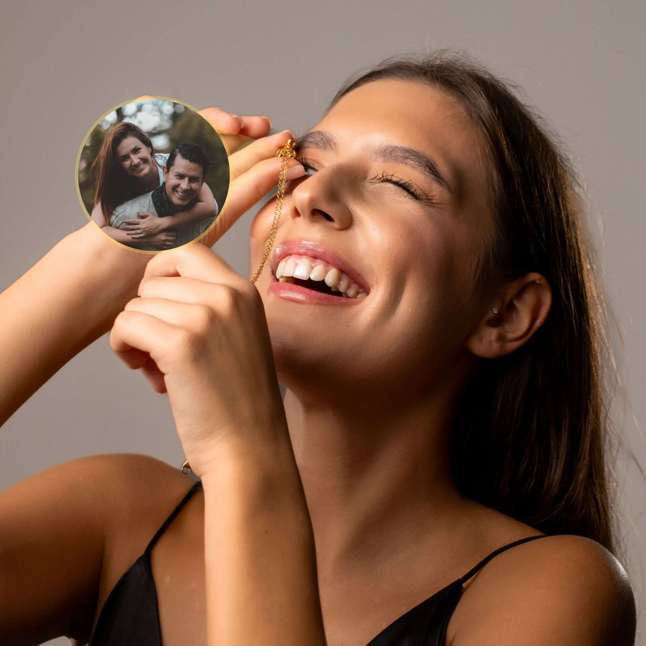 Happy woman holding Timeless Photo Necklace, featuring a photo of loved ones, by Brother & Sisters.