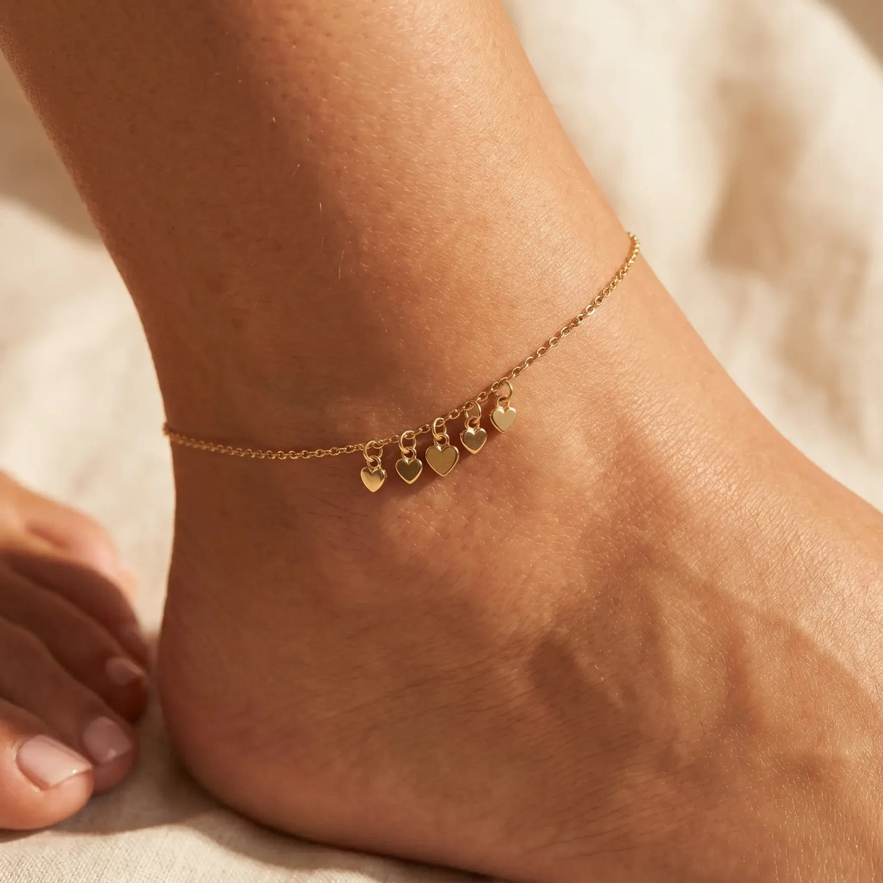 Tiny Heart Drop Anklet on ankle, featuring ultra-dainty gold chain with five tiny heart drops from Brother & Sisters.