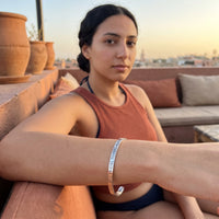 Thumbnail for Travel To Feel Alive bracelet in silver worn during a relaxed moment | SKU: ttfa-wg