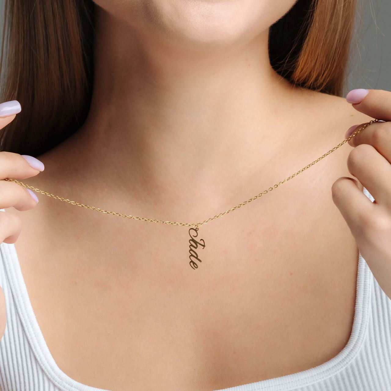 Vertical Name Necklace worn by a woman, featuring a personalized gold pendant displaying the name 'Pade' by Brother & Sisters.